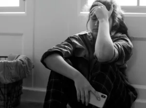 person experiencing PTSD triggers causing anxiety and emotional distress while sitting alone