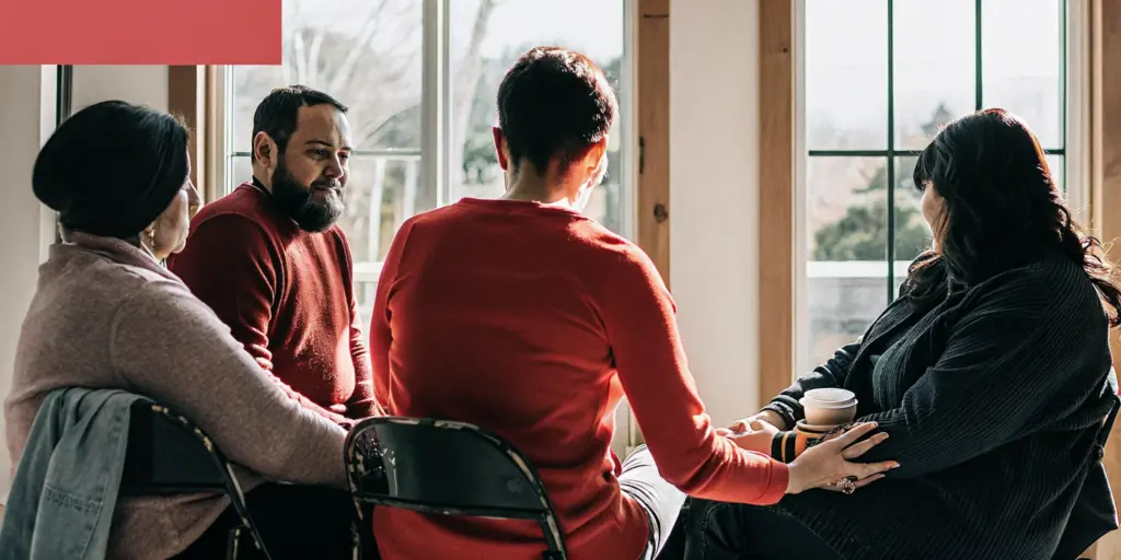 Group of people in a supportive recovery circle at a community center