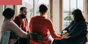 Group of people in a supportive recovery circle at a community center