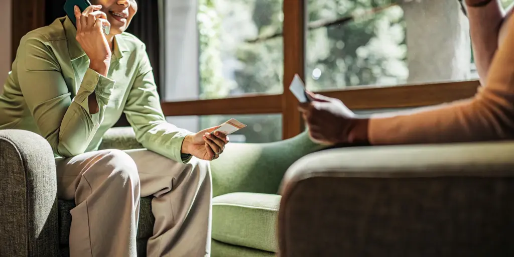 A person holding an insurance card while speaking on the phone about rehab coverage